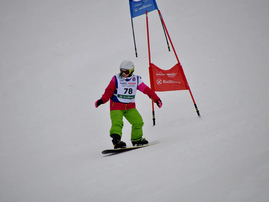 Snowboarderin mit Startnummer 78 umfährt ein rotes Tor.